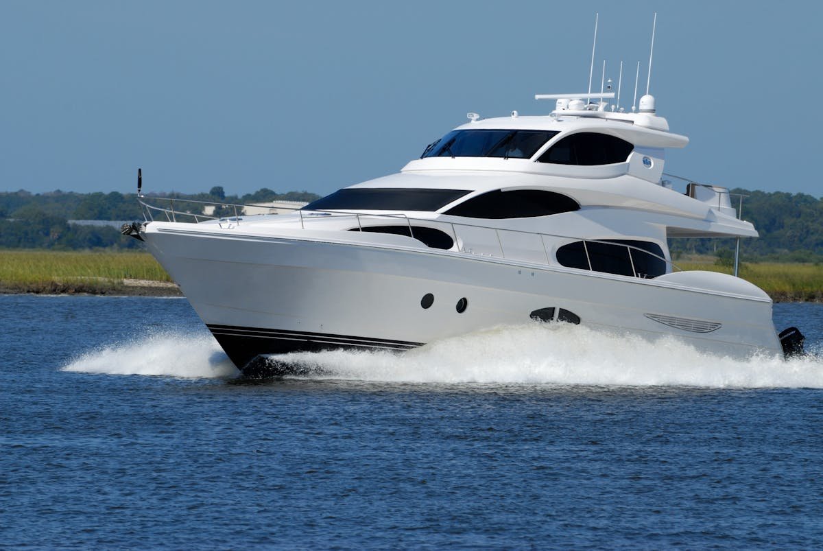 Luxury motor yacht cruising in turquoise tropical waters with island coastline in the background