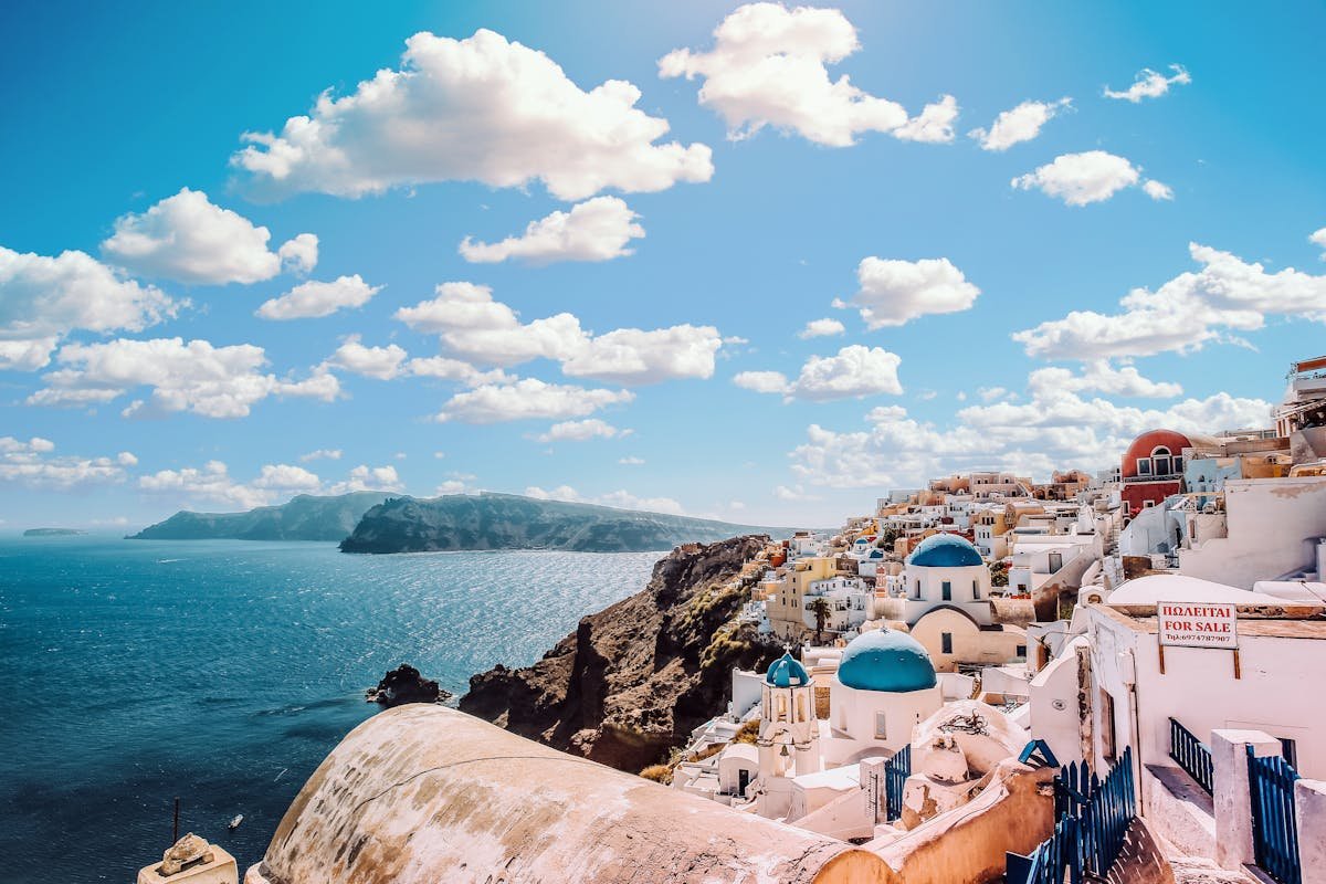 Panoramic view of Santorini's blue-domed churches and caldera overlooking the Aegean Sea